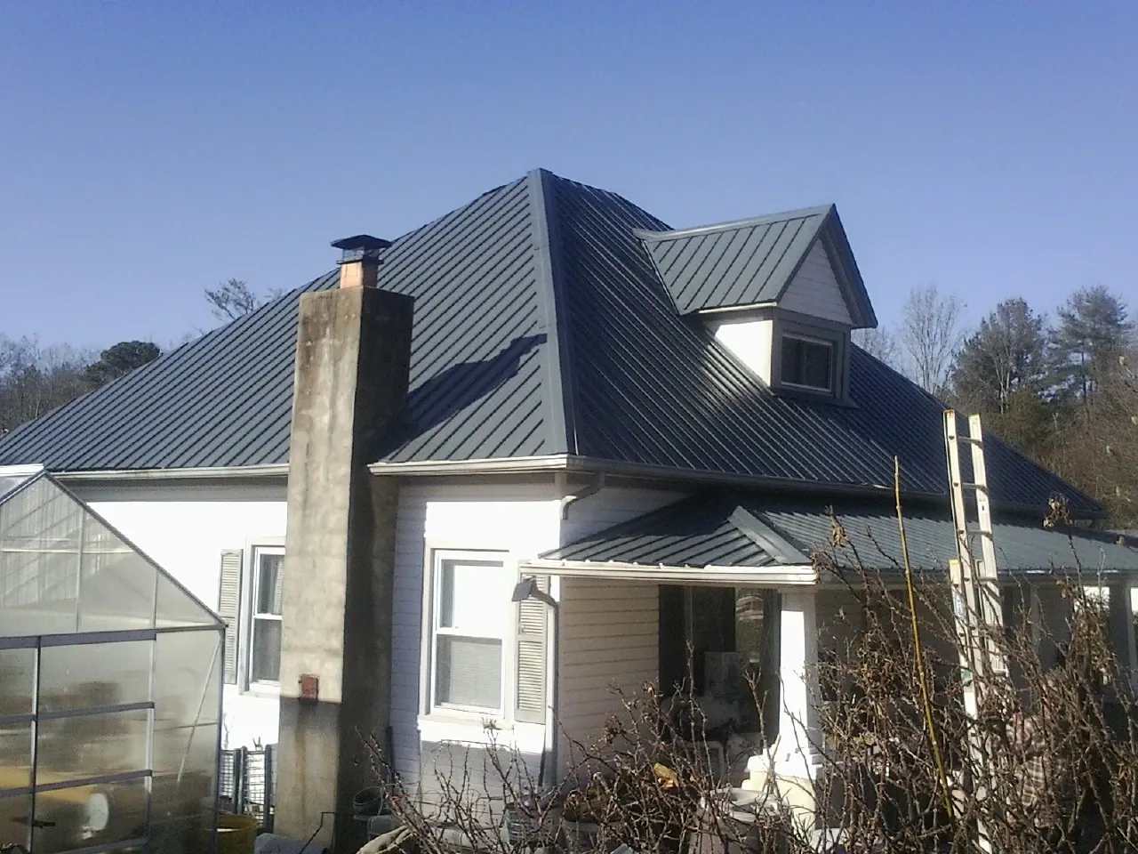Dark blue standing seam metal roof on a white farmhouse with dormer — Slate & Tile Roof Repair by Roofing Brothers in Spencertown