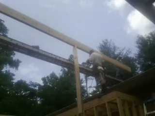 Carpenter setting a ridge beam over a new addition frame — Ice Dam Removal by Roofing Brothers in Spencertown