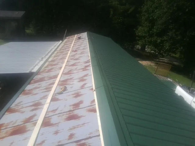 Old rusted panels beside newly installed green metal roofing — Wind Damage Roof Repair by Roofing Brothers in Spencertown
