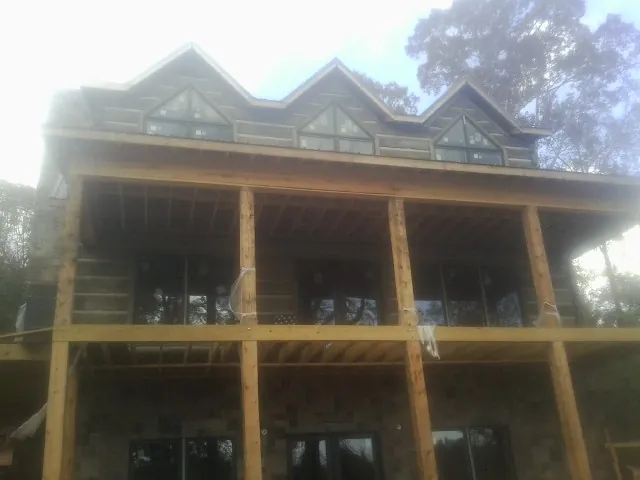 Dormers and porch framing on a large log home under construction — Roof Coating work by our crew in Spencertown