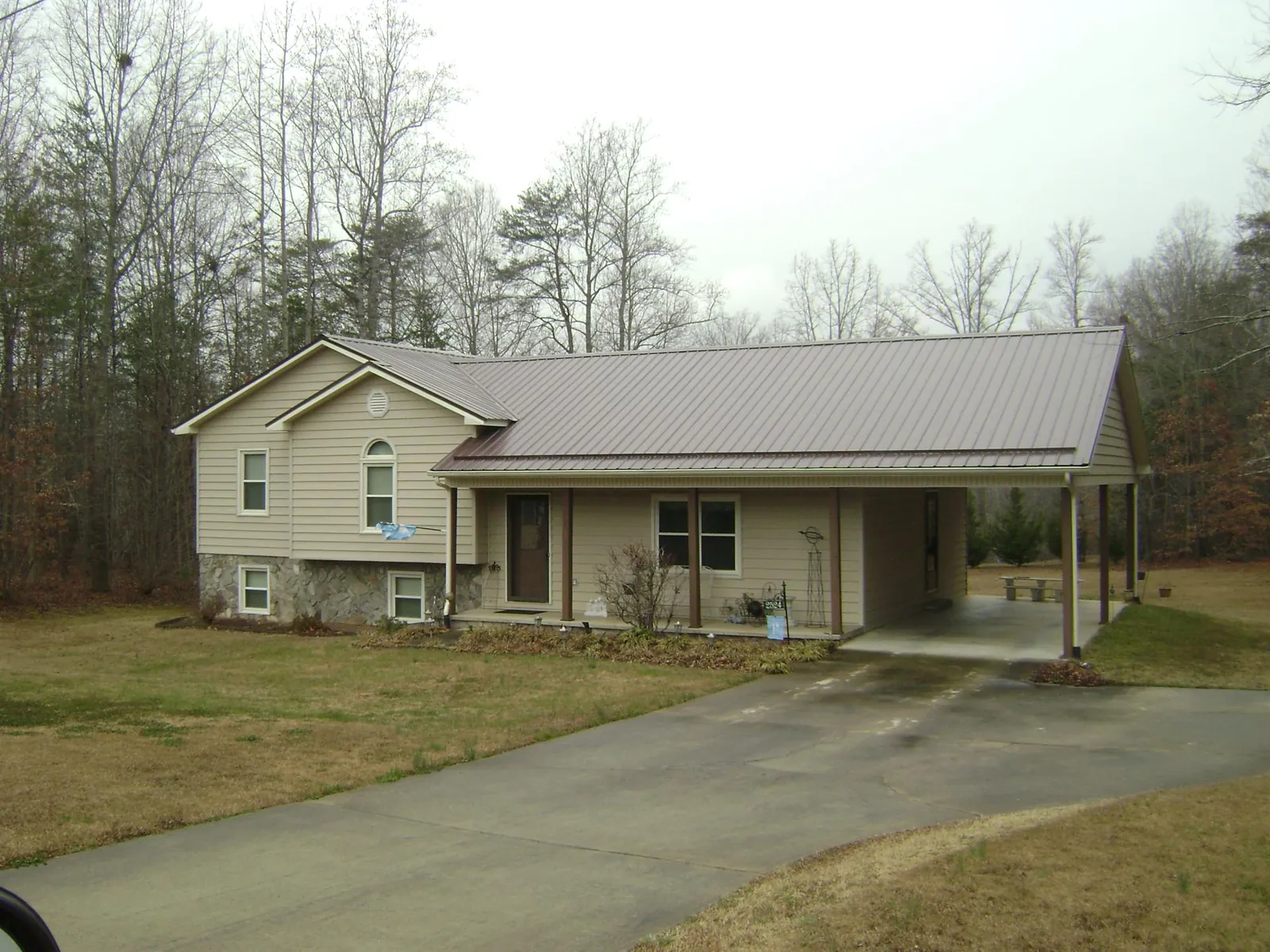 Brown metal roof on a tan split level home with an attached carport in Spencertown