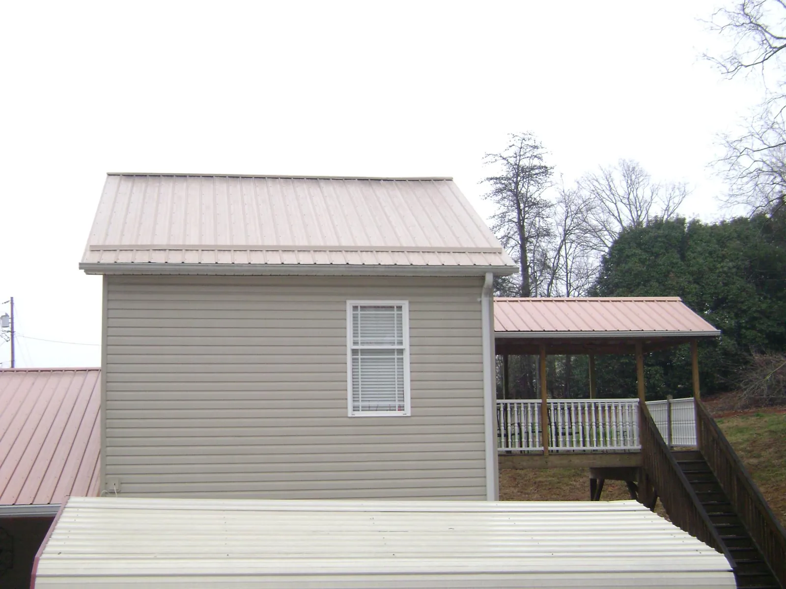 Tan metal roofs on a two story addition and attached porch, from a Roof Replacement job in Spencertown